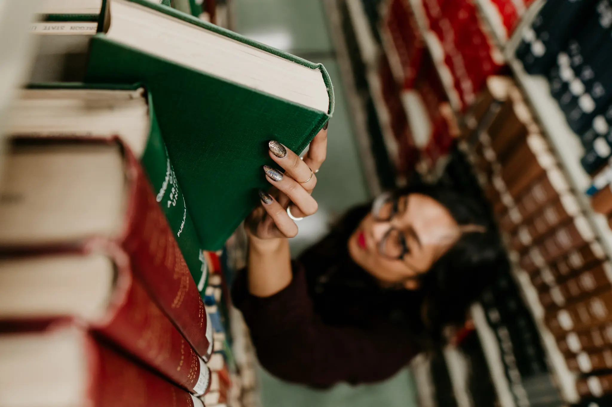Overhead view of woman pulling a book from a bookshelf