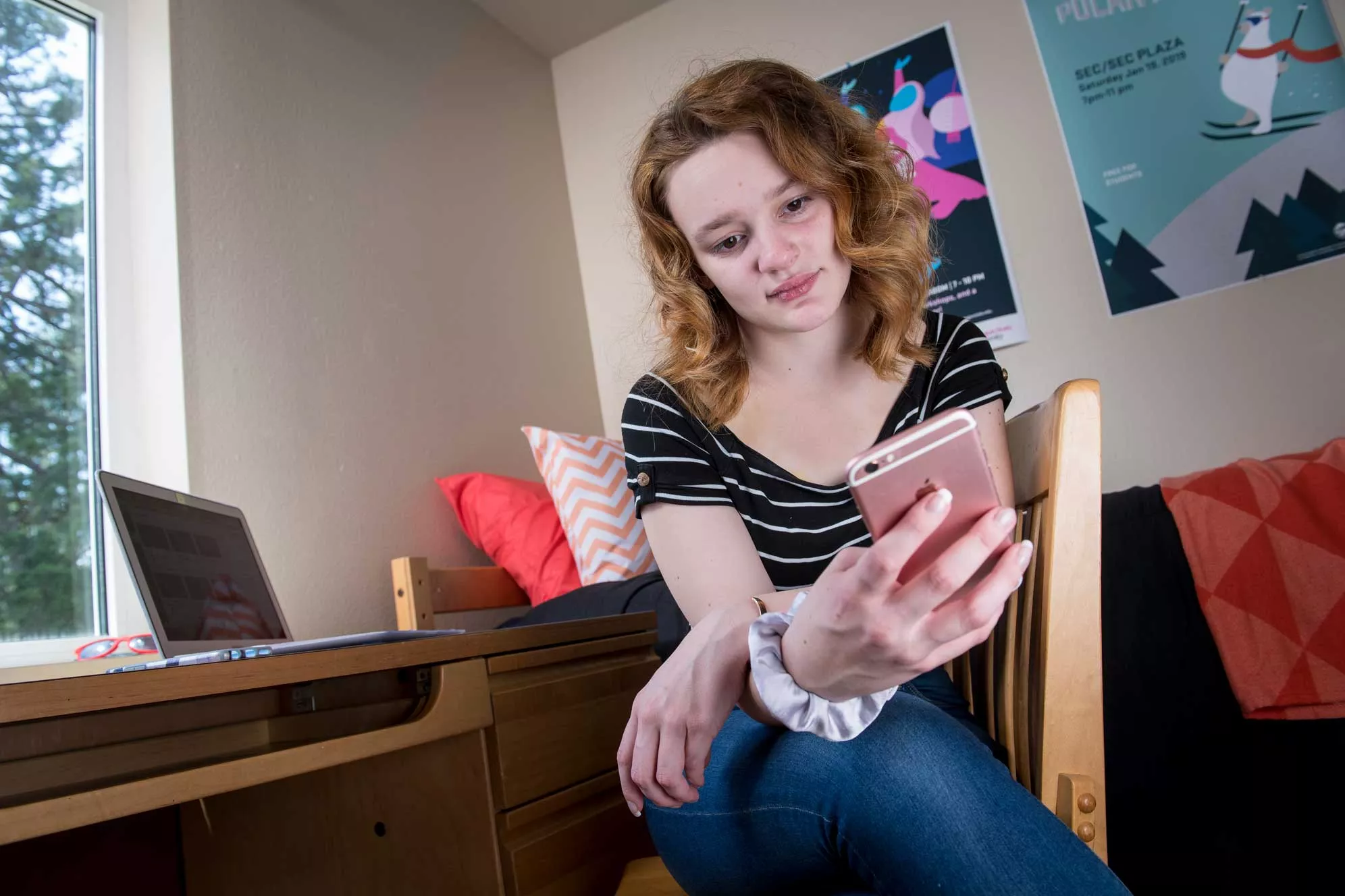 female student sitting in room looking at her phone