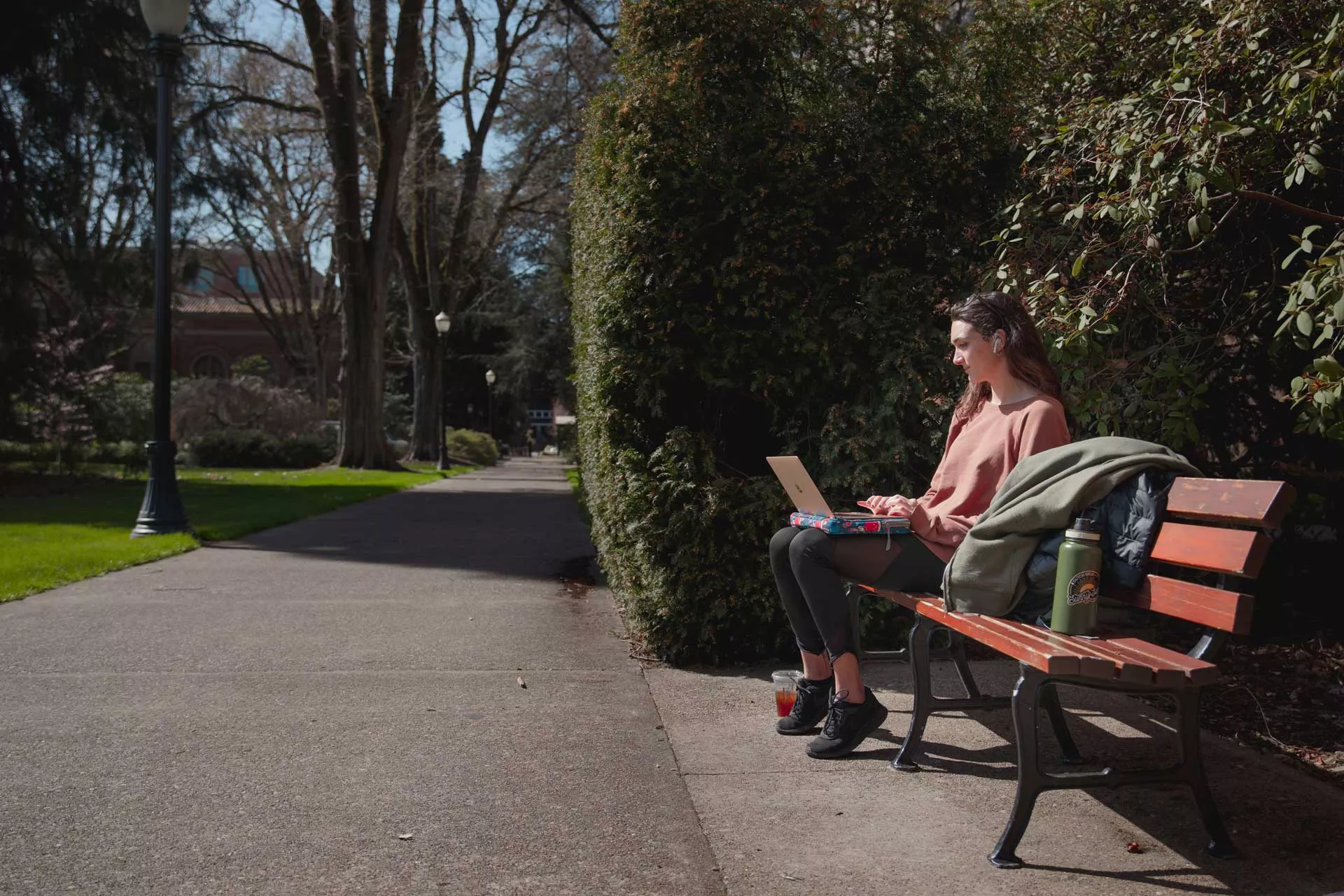 student sitting on bench typing on laptop